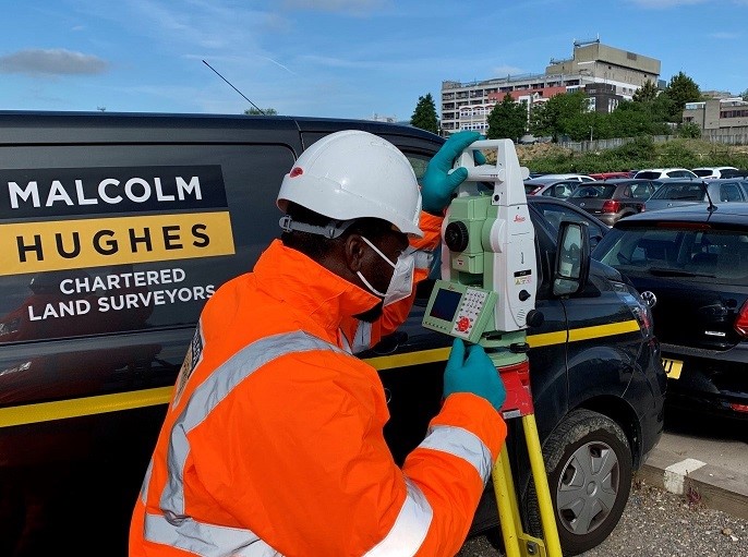 Malcolm Hughes colleague looking through total station