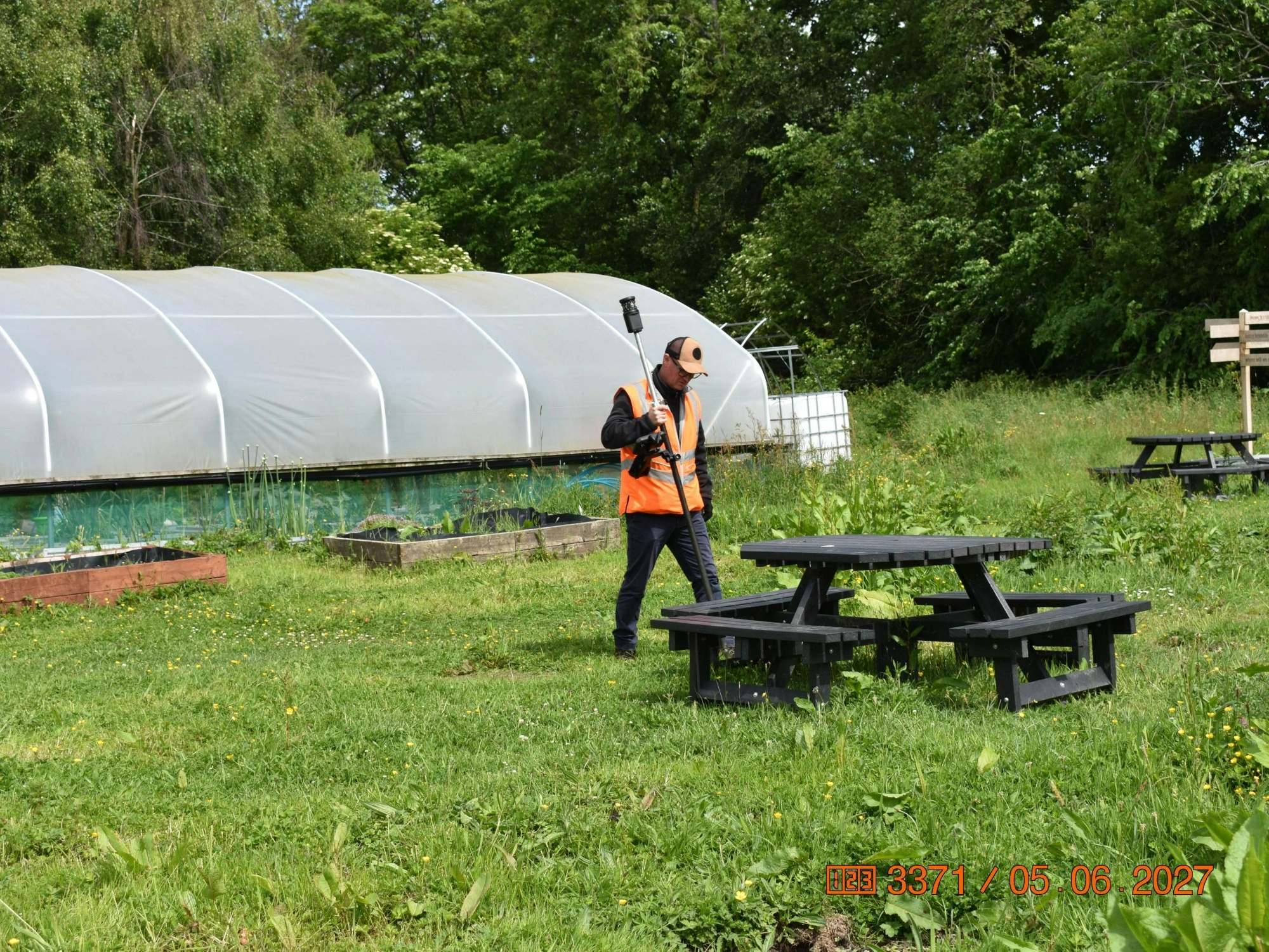 An MHLS land surveyor in an orange high-vis jacket, conducting a topographical survey of Bramble Woods.