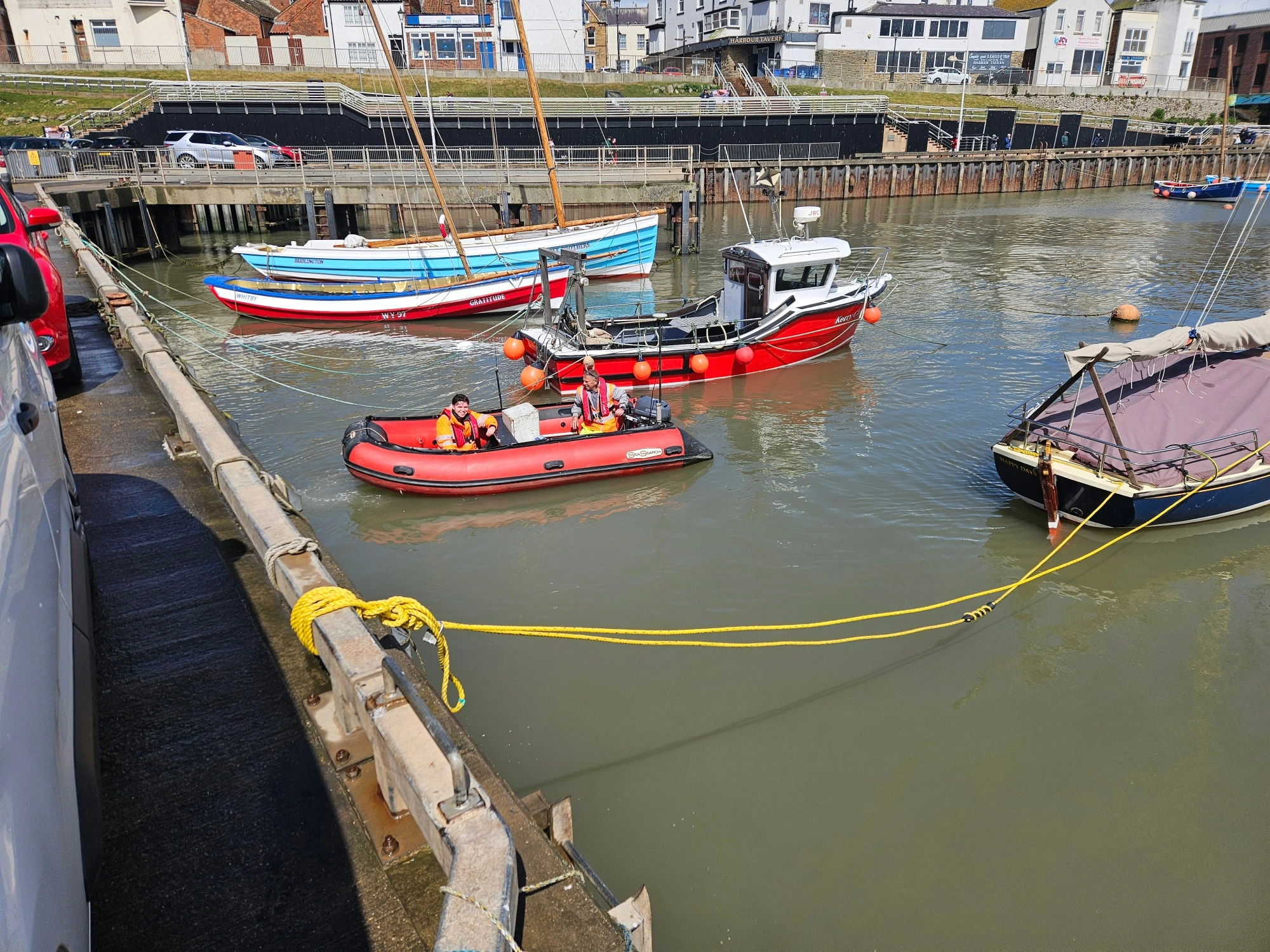 MHLS survey technicians in a small red boat in Bridlington Harbour.