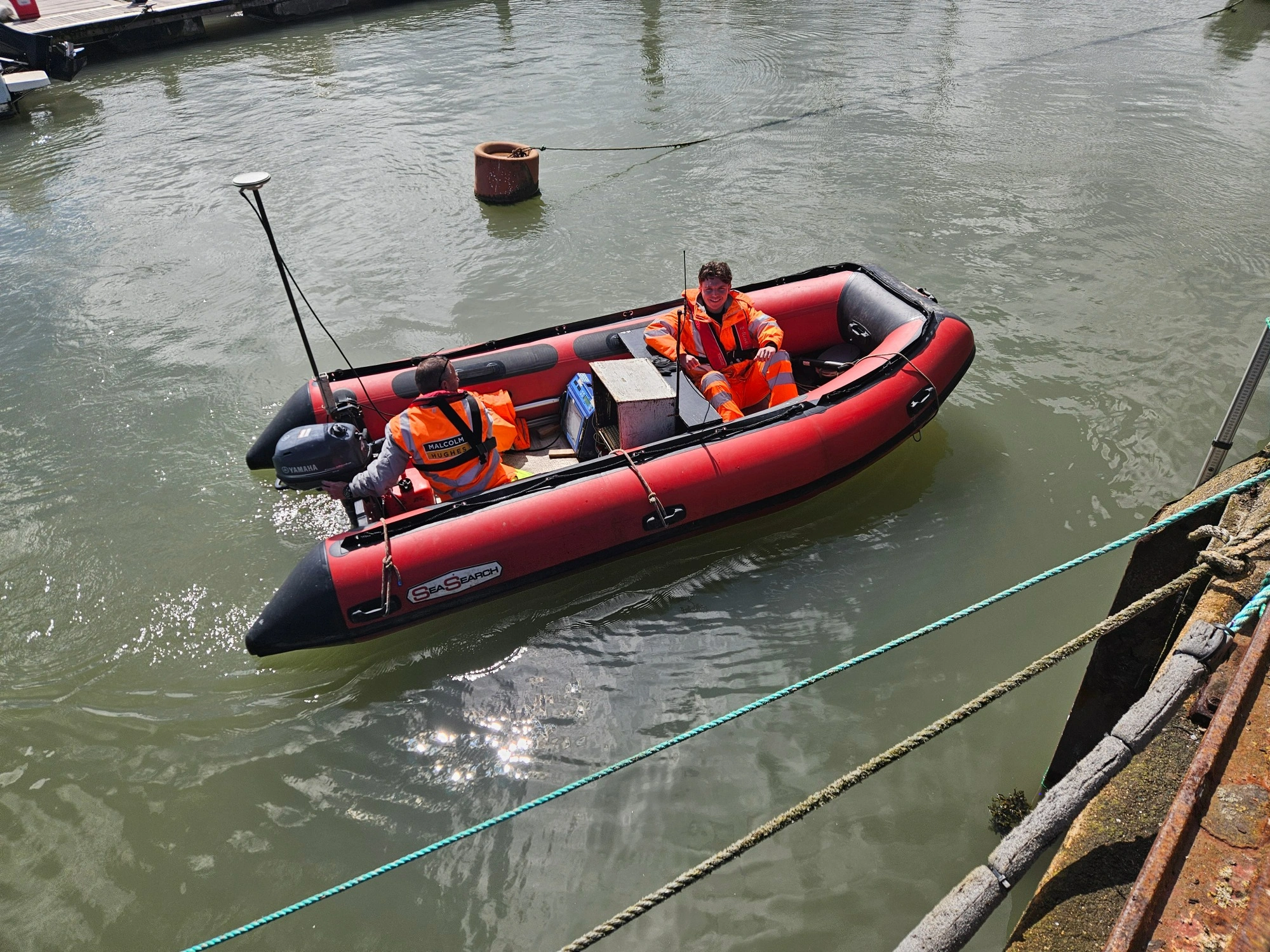The MHLS team delivering a bathymetric survey of Bridlington Harbour in a small red boat.