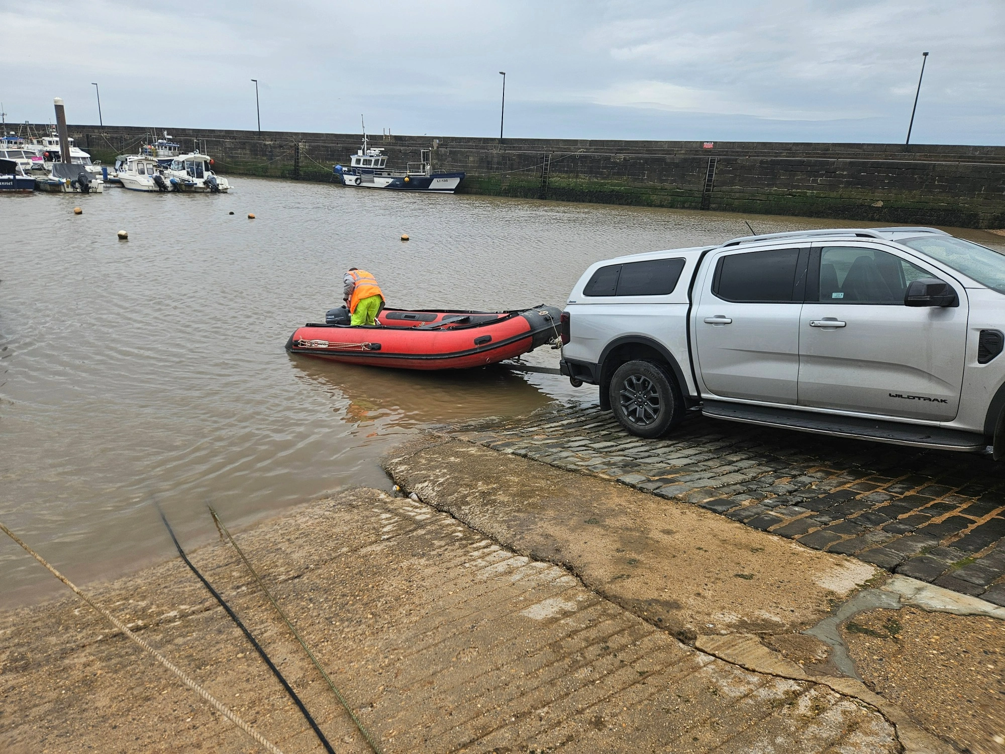 MHLS-bridlington-harbour-case-study (1)-1 A silver car pulling an MHLS land surveyor in an orange boat out of thw water at Bridlington Harbour.