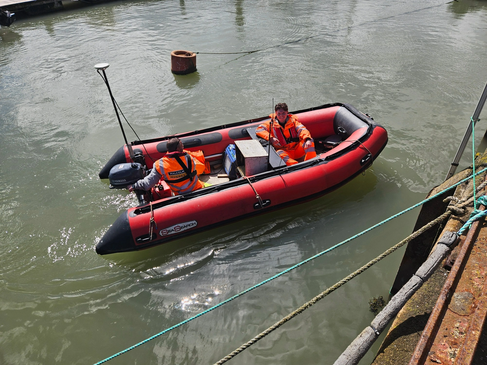 MHLS-bridlington-harbour-case-study (1)-9 Two MHLS land surveyors in an orange boat on the waters at Bridlington Harbour.